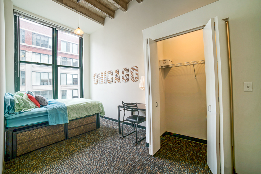 Model bedroom with large closet and underbed storage at Tailor Lofts